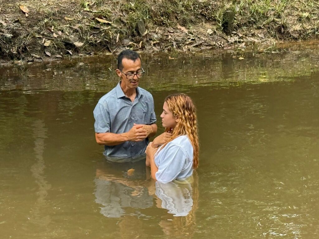 A pastor baptising a young woman in a river in Brazil