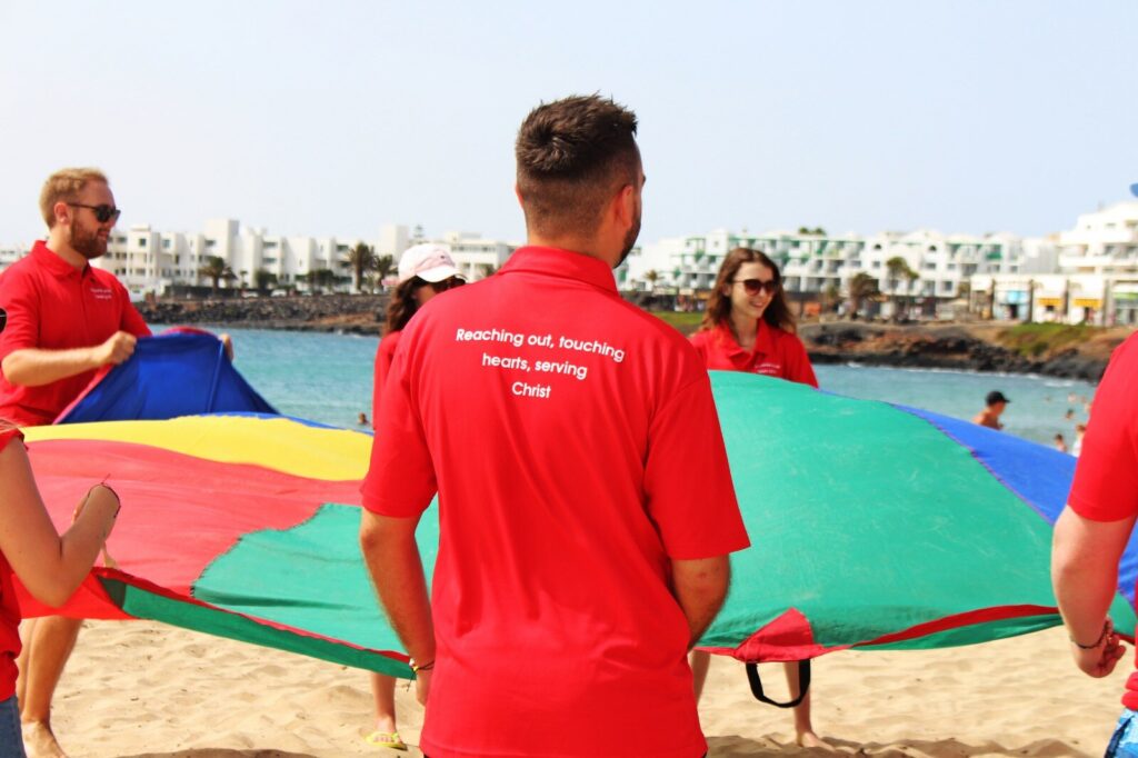 An Acre mission team playing a parachute game with children on a beach in Lanzarote